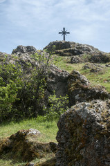 Fototapeta premium Christian cross on rocky mountain hill on blue sky background