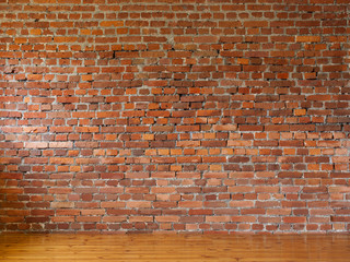 Room with red brick walls and wooden flooring of boards
