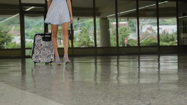  Legs of pretty woman with luggage and dressed in high hills shoes and dress