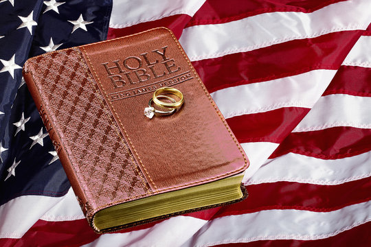 Holy Bible with Wedding Rings on American Flag Concept