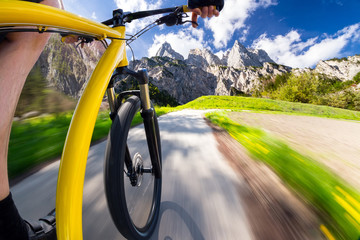 onboard view of fast moving yellow bicycle mountain bike in front of mountains / mountainbike...