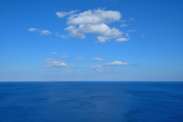 Fototapeta na wymiar Vast deep blue sea with white clouds