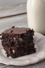 Decadent dark chocolate chip brownie with antique milk bottle on an old weathered barn wood table