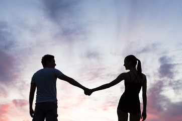 Romantic couple holding hands at sunset. 