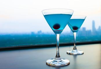 Pair of cocktail glasses in a high rise restaurant setting. 