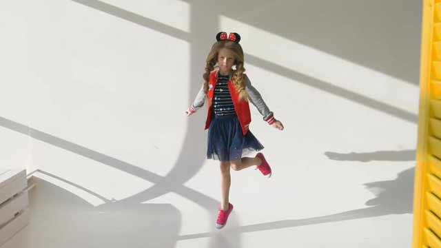 Little girl with long braids in a red jacket. Posing in the studio, 