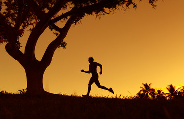 Male runner running at sunset. 