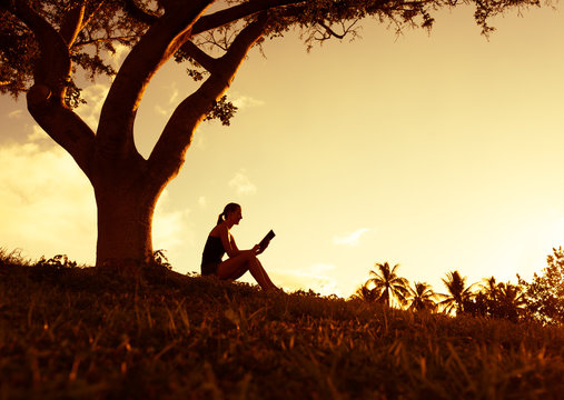 Young woman reading a book in the park.