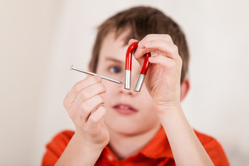 Close up on boy playing with nail and magnet