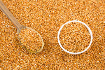 Millet cereal grains with bowl and wooden spoon.