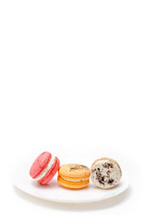 Collection of brightly colored French macarons on white plate and white background