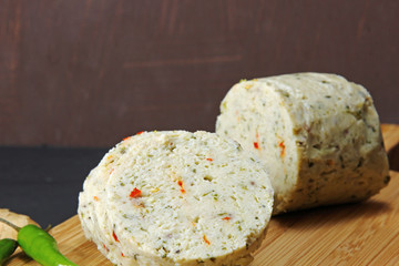 Slices of homemade spicy chicken salami with ginger, garlic, cilantro and red pepper on a moody background with copy space, selective focus.