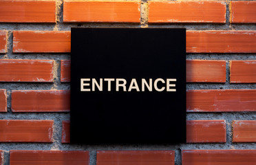 Black entrance sign on brick wall background