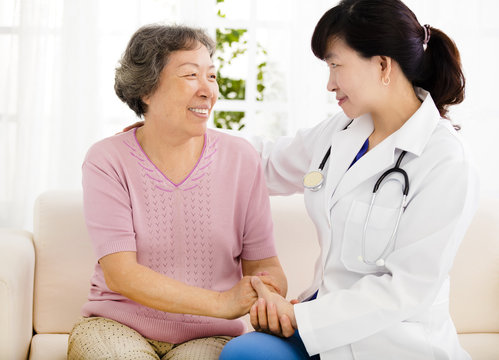 Nurse holding hand of senior woman in rest home