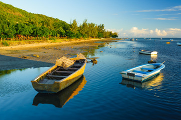 Fototapeta na wymiar Fishing boats on the background of incredible golden sunset. Mauritius Island