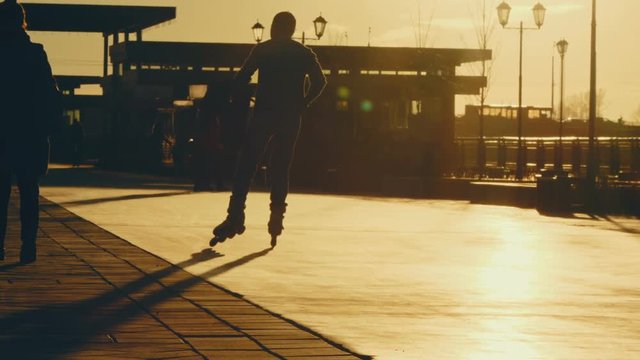 Silhouette of a man rollerblading at sunset in modern city