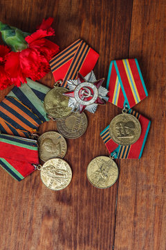 Order of the Patriotic War in St. and Medals for the victory over Germany and two red flower on a table. close up. selective focus image