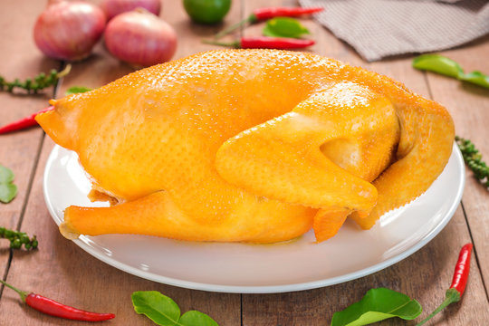 Whole boiled chicken with vegetables on wooden table prepared, C