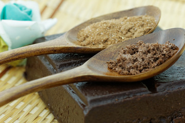 Dark chocolate powder and cocoa powder in wooden spoon with dark chocolate bar.
