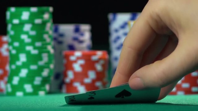 Person playing poker at casino, getting bad cards. Loss, addiction to gambling