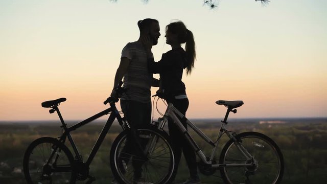 Silhouette of lovers with bicycles at sunset. 