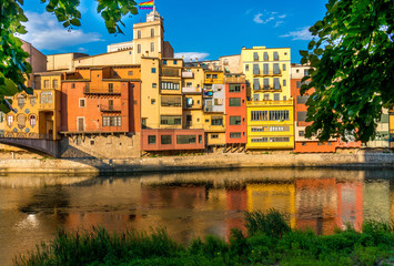 Fototapeta premium Colorful yellow and orange houses and bridge Pont de Sant Agusti reflected in water river Onyar, in Girona, Catalonia, Spain.