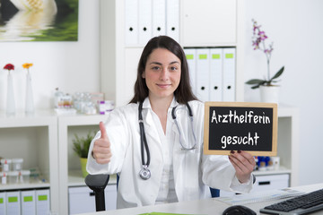 Junge Ärztin bzw. Arzthelferin hält Hinweisschild zur Jobsuche m