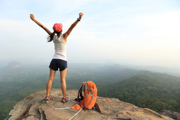 cheering young asian woman hiker open arms on seaside mountain peak