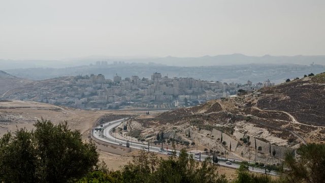 Traffic at Derech Har HaTzofim tunnel road in Jerusalem (Israel) with the town of alZa'im and the haze of the desert at the background.