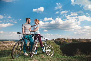 Beautiful young couple in love walking with bicycles hugging and looking at each other. The concept of joy and happiness