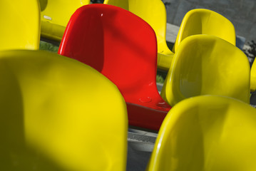 Close-up shot plenty of yellow and one red plastic seats at stadium
