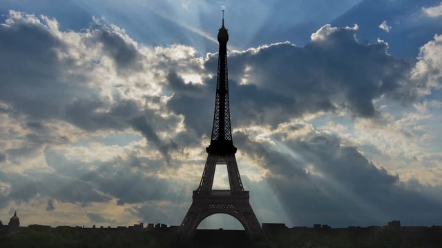Time lapse of crepuscular rays behind silhouette of Eiffel tower and Paris skyline.