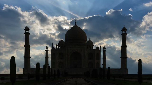 Time lapse of crepuscular rays behind silhouette of Taj Mahal.