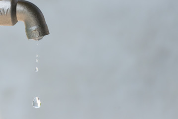 leaking silver faucet with water drop, close up, copy space