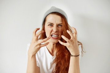 Close up isolated portrait of young annoyed angry woman holding hands in furious gesture. Young...
