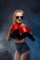 beautiful sexy blonde boxer girl dressed in red gloves, sunglasses and black lingerie. studio...