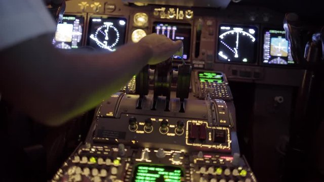 Detail shot of airline pilot pulling back on jet throttles in the cockpit of a jumbo jet.  Rear view, hand-held with fast changing movement and racking focus, originally recorded in 4K.