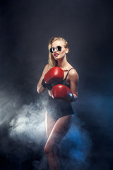 beautiful sexy blonde boxer girl dressed in red gloves, sunglasses and black lingerie. studio...