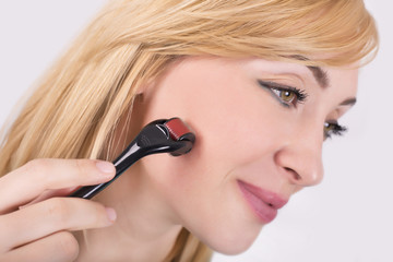 Close up of woman using derma roller. Roller ,microneedle, rejuvenating, beautification, skin care.