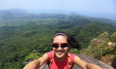 Naklejka premium young woman hiker use smartphone taking self photo on seaside mountain top