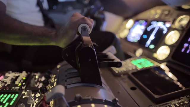 Detail shot of airline pilot pushing throttle forward in the cockpit of a jumbo jet.  Side view, hand-held camera, originally recorded in 4K.