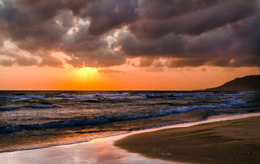 Fototapeta na wymiar Sunrise over the sea, the rolling calm waves, sandy beach. Skay orange, pink clouds
