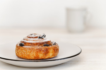  Cinnamon roll with raisins in a ceramic saucer