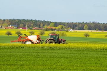 traktor rolniczy podczas oprysków chemicznych na wiosennym polu © Mike Mareen