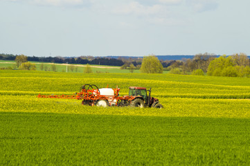 traktor rolniczy podczas oprysków chemicznych na wiosennym polu