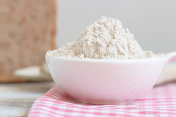 Bowl with flour on a tablecloth and some bread. Empty copy space for editor's text.