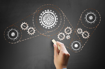 Man drawing gears on blackboard
