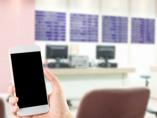 blank smartphone in hand blurred hospital information desk background, focus at smartphone