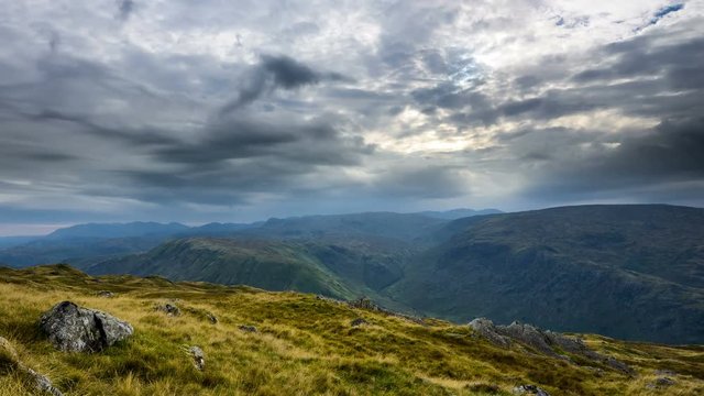 Crepuscular rays breaking through clouds in Lake District, England. Time lapse, zoom in and pan right.