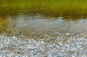River stones background. Riverside with round white stones and clear water.